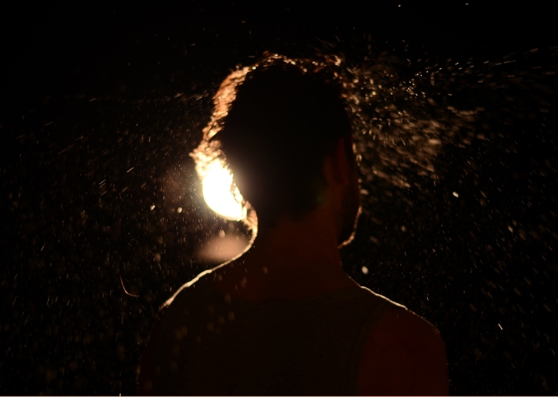Die Silhouette eines Mannes im Gegenlicht, umgeben von aufspritzendem Wasser.