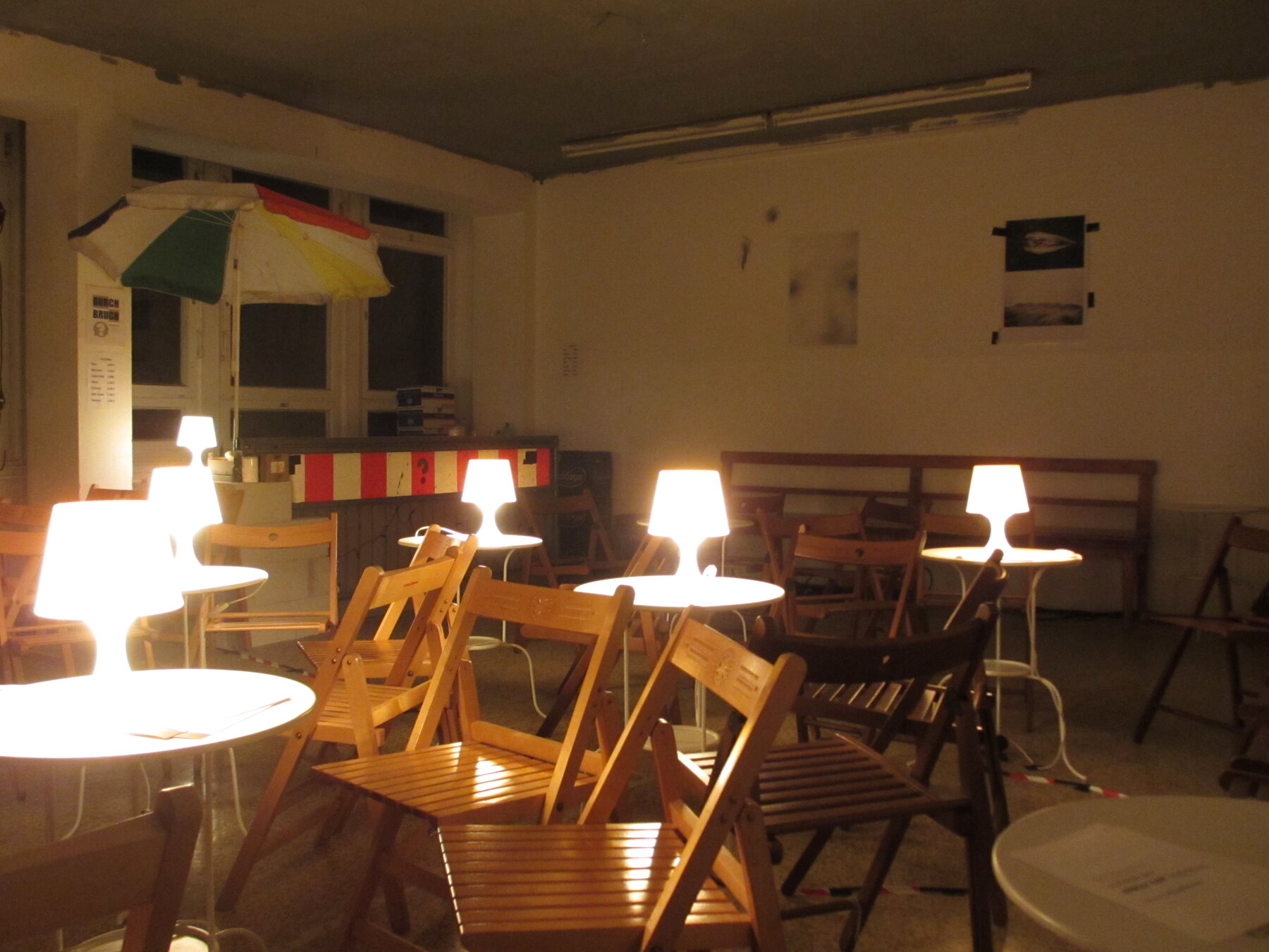 Kleine Tische, Stühle und leuchtende Tischlampen im Durchbruch.
